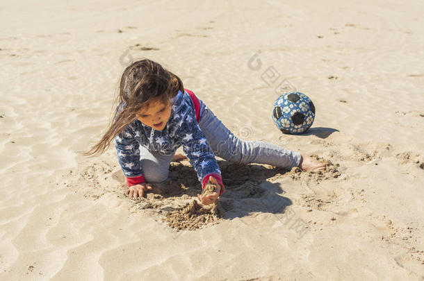 在复活节的一个<strong>刮风</strong>的日子里，女孩在海滩上玩沙子