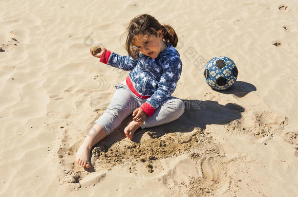 在复活节的一个<strong>刮风</strong>的日子里，女孩在海滩上玩沙子