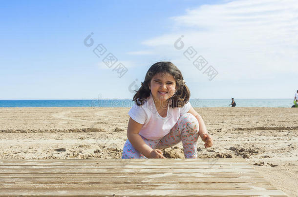 女孩在春天一个阳光明媚的日子里在海滩上玩沙子