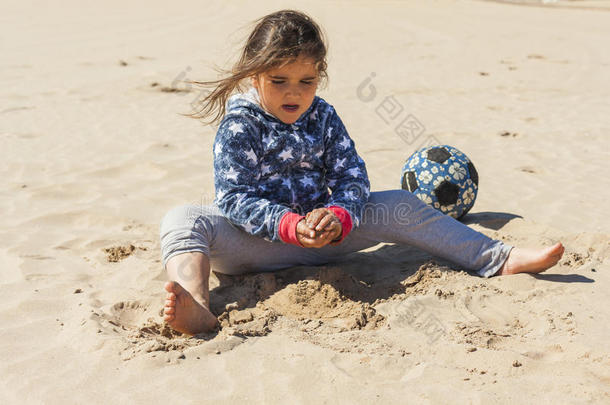 在复活节的一个刮风的日子里，女孩在海滩上玩沙子
