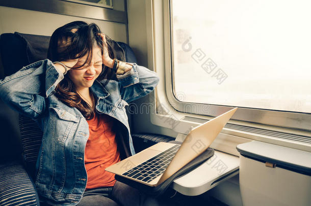 亚洲大学女孩沮丧的笔记本电脑在火车上，温暖的灯光色调，与复制空间