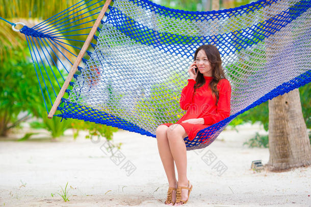 美丽的女人在热带海滩的吊床上放松
