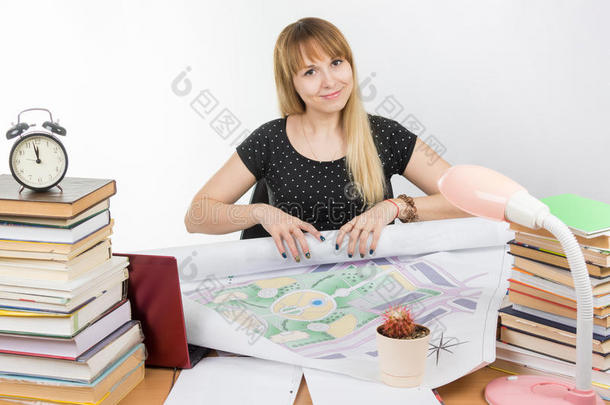 女孩设计学生在他的桌子上微笑着转身滚动完成的绘图项目