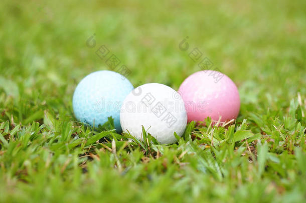 高尔夫球场绿草地上的高尔夫水晶白色、粉红色和蓝色球