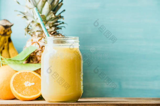 新鲜混合黄色和橙色水果冰沙在玻璃瓶与稻草