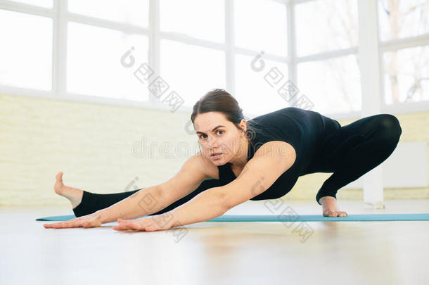 美丽的瑜伽女子在培训大厅的背景下练习