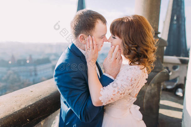 可爱的已婚夫妇抚摸着对方的脸，紧紧地站在有<strong>柱子</strong>的古董阳台上