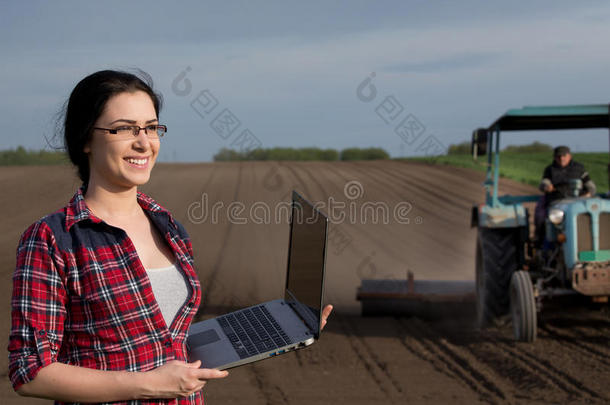 农民女孩带着笔记本电脑在田里用拖拉机