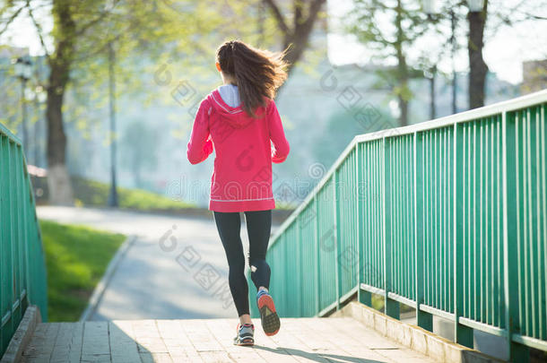 在桥上锻炼的跑步女子的后视图
