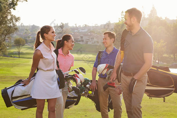 一群高尔夫球手背着高尔夫球袋沿着球道行走
