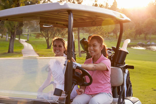 女高尔夫球手沿着高尔夫球场的球道驾驶马车