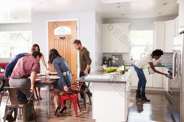 一群朋友坐在桌子旁，在家里举行晚宴