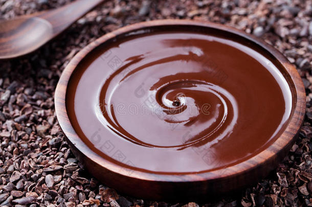 一碗融化的巧克力和木制<strong>勺子</strong>在<strong>一个</strong>粉碎的生可可豆，笔尖的背景复制空间。