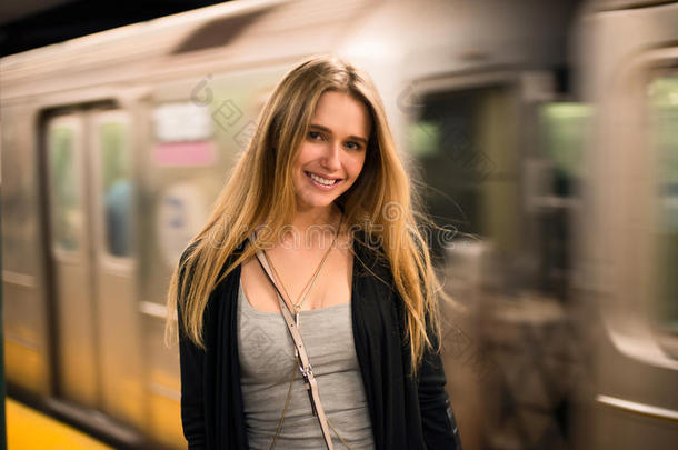 美丽的微笑女孩站在<strong>地铁</strong>站台<strong>上</strong>，面对即将到来的<strong>地铁</strong>列车