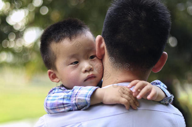 <strong>中国</strong>小男孩拥抱他父亲。 这个男孩沉思地看着一<strong>边</strong>
