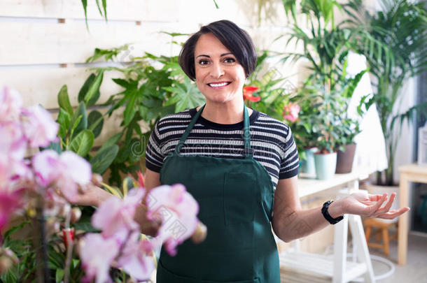 快乐的女人花店在盆栽植物中微笑