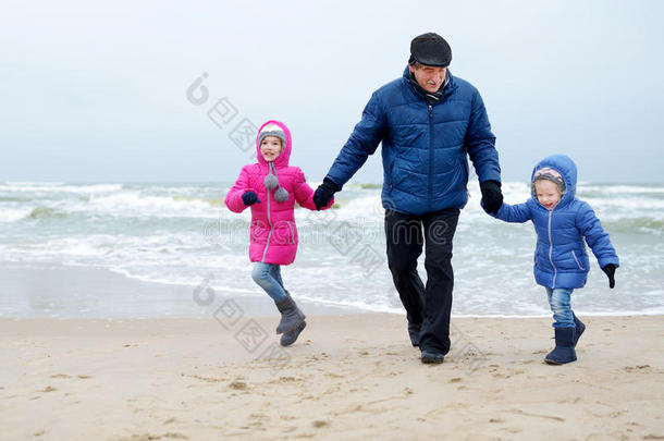 可爱的小女孩和他们的爷爷在冬天的<strong>海边玩耍</strong>