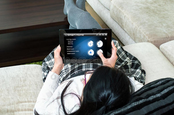 一个女人正在选择平板电脑的smarthome应用程序的类型