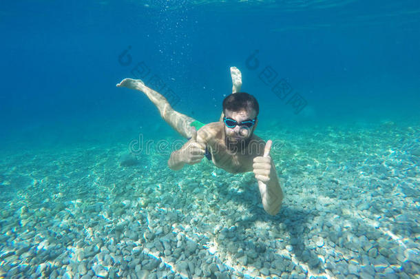 带着面具的胡子男人在蓝色干净的水里潜水