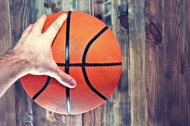 篮球在木制硬木地板上用手抓着。