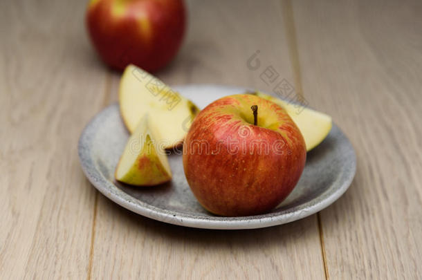 新鲜的红<strong>苹果切片</strong>在盘子上，发现了天然的木制背景