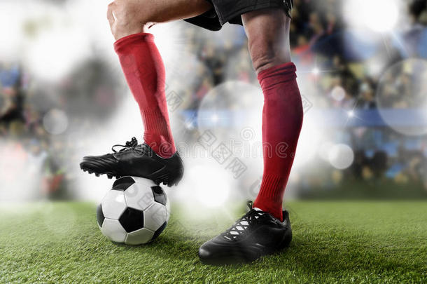 足球运动员穿着红色袜子和黑色鞋子，与球站在球场上