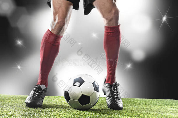 足球运动员穿着红色袜子和黑色鞋子跑步和运球，球在体育场比赛
