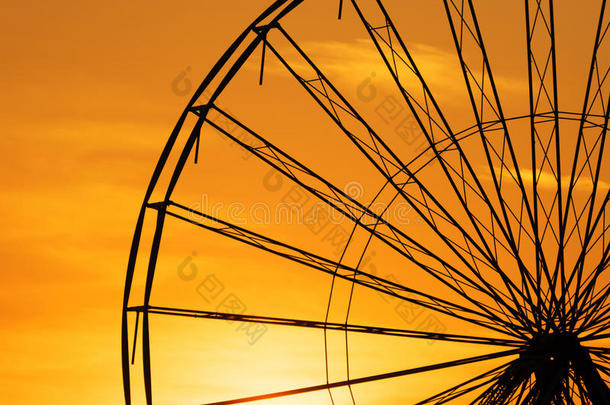 抽象的背景，摩天金属轮对抗天空与日落。