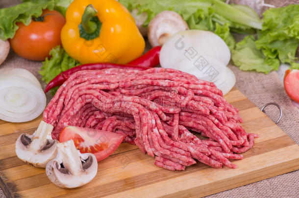 新鲜的生肉在砧板上，上面有蔬菜和蔬菜