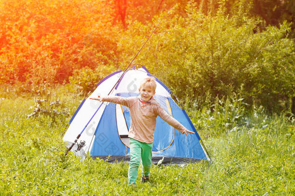 可爱的小男孩在大自然背景的帐篷附近快乐地奔跑。