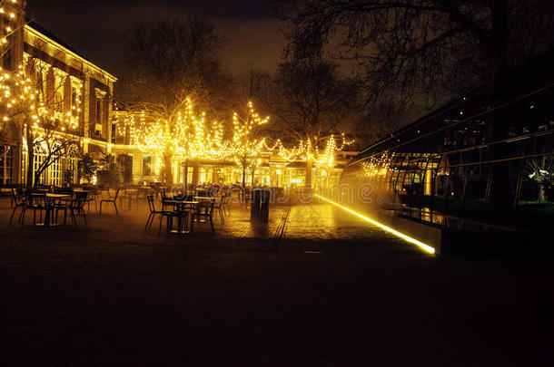 空夜餐厅，许多桌椅无人，神奇的仙女灯在树上，如圣诞节