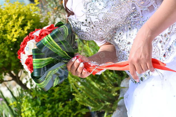 新娘的手，穿着一件白色的连衣裙，带着一束<strong>鲜红</strong>的花