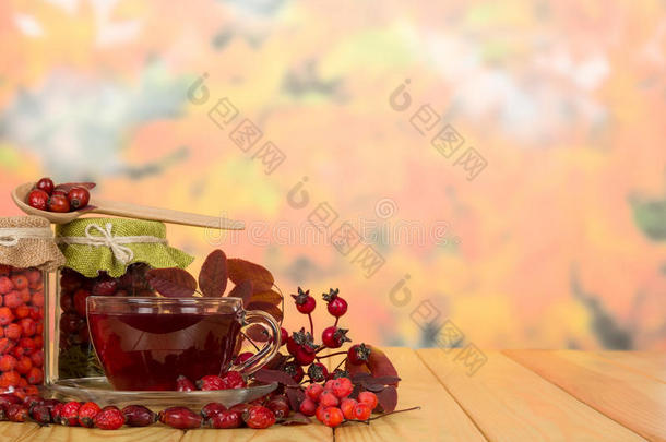 浆果和背景秋叶上的杯茶。