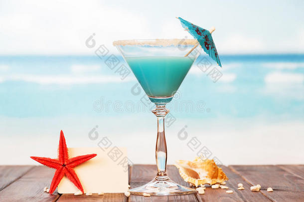 空白卡，鸡尾酒，海星和贝壳在沙子对海。