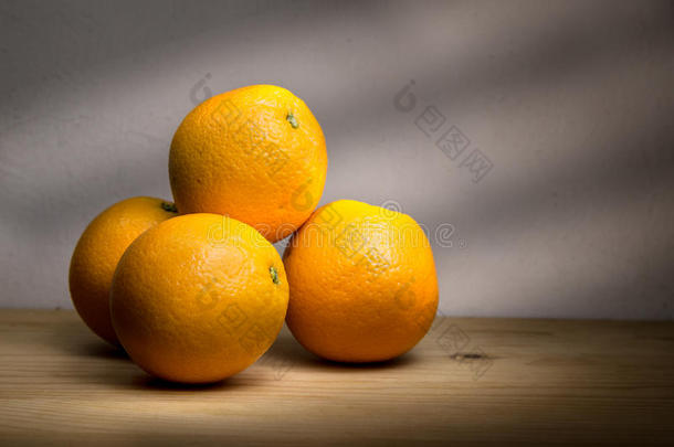 四个新鲜的<strong>橘子</strong>放在木桌上，光线明亮
