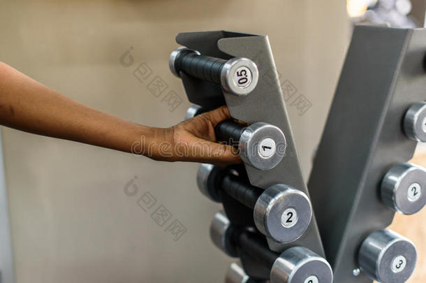 在健身房里特写强壮女人的手拿着沉重的哑铃。 健身概念