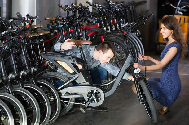 雇员帮助成年男子选择自行车在租赁机构