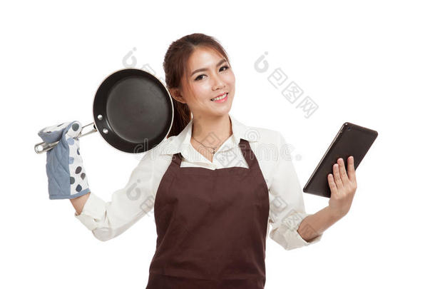 亚洲美丽的女孩烹饪与煎锅阅读平板电脑