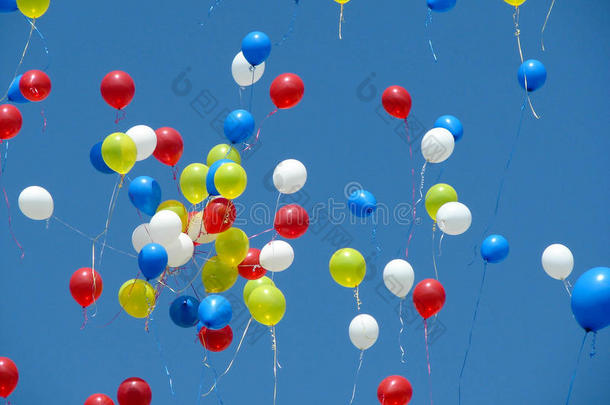 鲜红、黄色、蓝色和白色的气球释放到蓝天中。