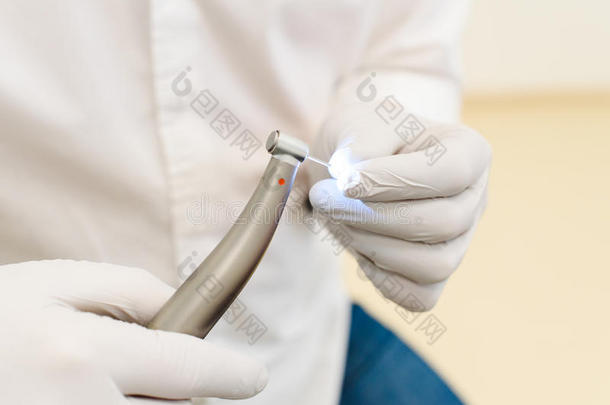 牙科医生的手戴着白色乳胶手套，拿着带涡轮的牙科钻机，特写