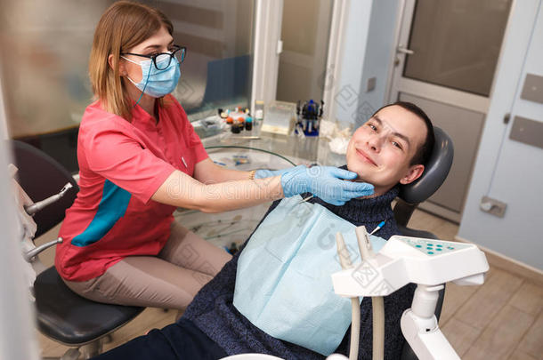 牙医检查他病人的牙齿。 在牙科诊所的行动