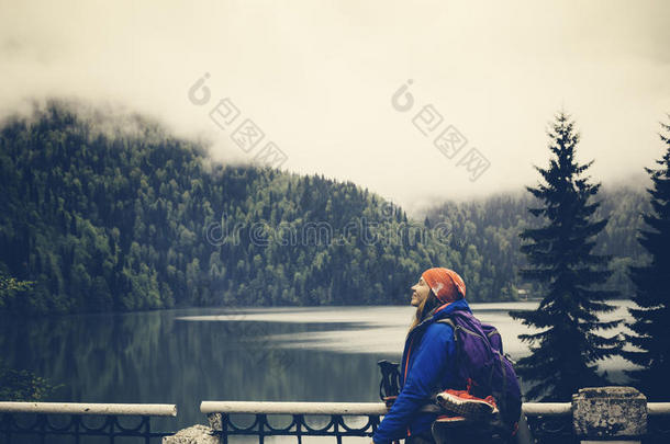 女孩在有山的背景湖上放松。 徒步旅行和背包休息。 旅行生活方式概念之旅。 满意和哈