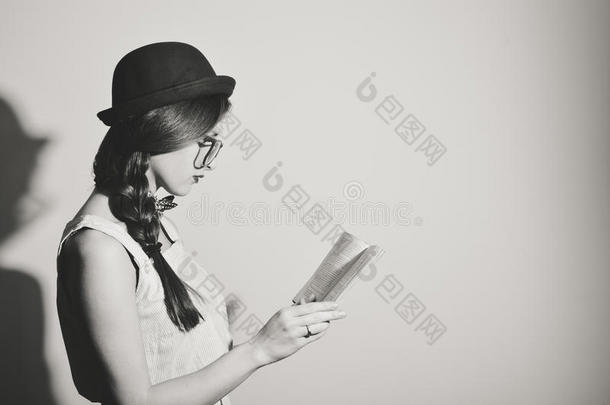 <strong>黑白图片</strong>，美丽的女孩阅读一本书在轻墙背景