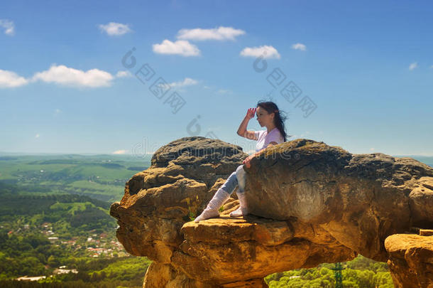 一个女孩坐在悬崖边上，望着远处
