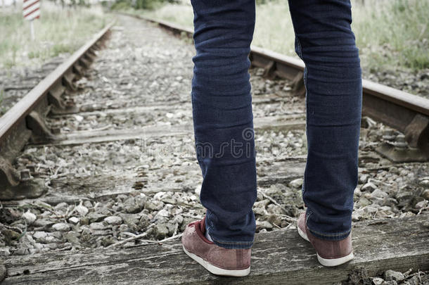 站在铁轨之间的人的脚的特写