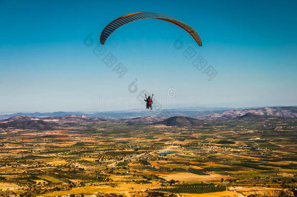 一架滑翔伞在蓝天的背景下飞过风景如画的田野