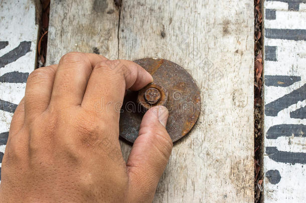 手工人在木头上安装生锈的螺母和螺栓