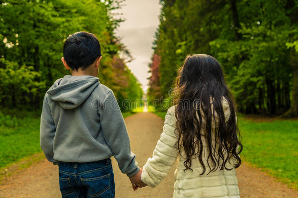 男孩和女孩牵手，面对通往远方的道路