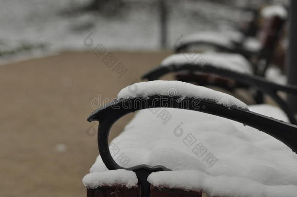 公园里的长凳。 雪躺在座位上。 冬天。 在外面走来走去