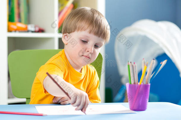 可爱的小男孩正在托儿所用<strong>彩色铅笔画</strong>画
